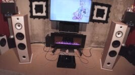 Two large Triangle Borea BR10 speakers are positioned on either side of a TV and fireplace unit